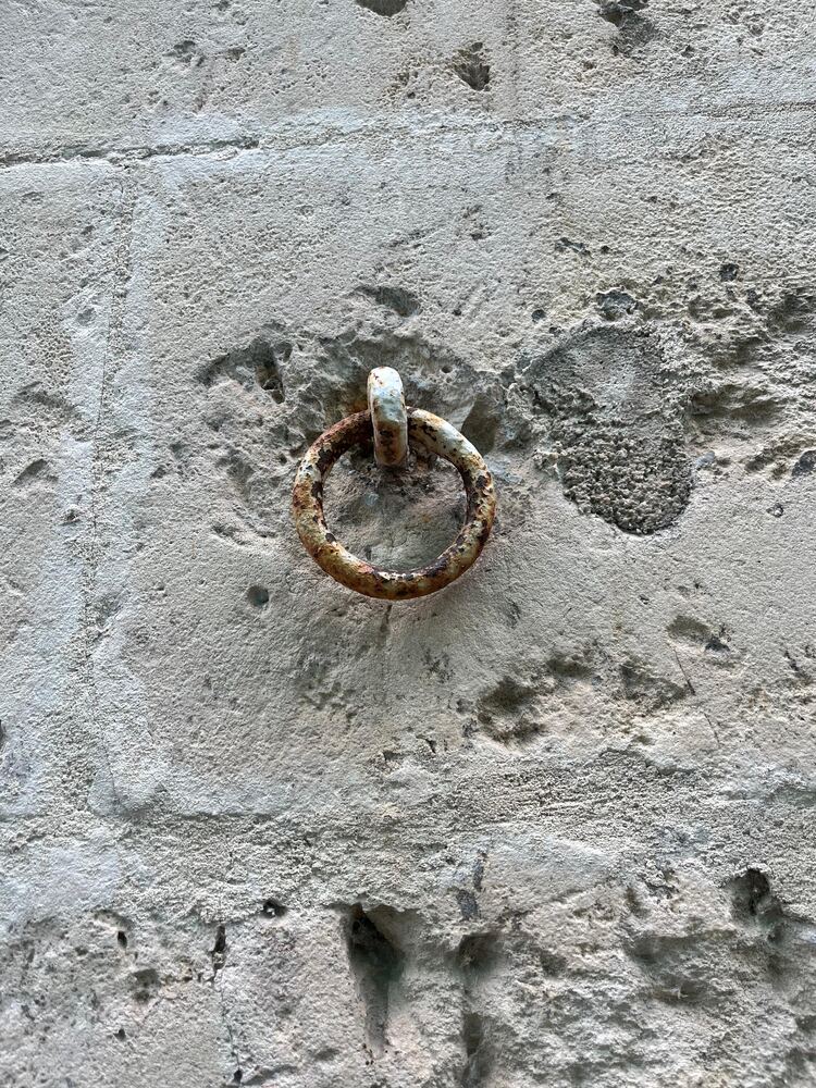 Anneau de fer ancien, fixé dans un mur de pierre.