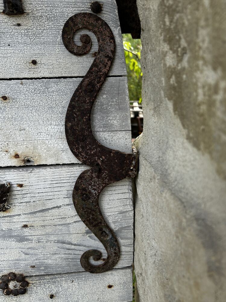 Charnière en fer forgé, en volute, sur une porte en bois ancienne.