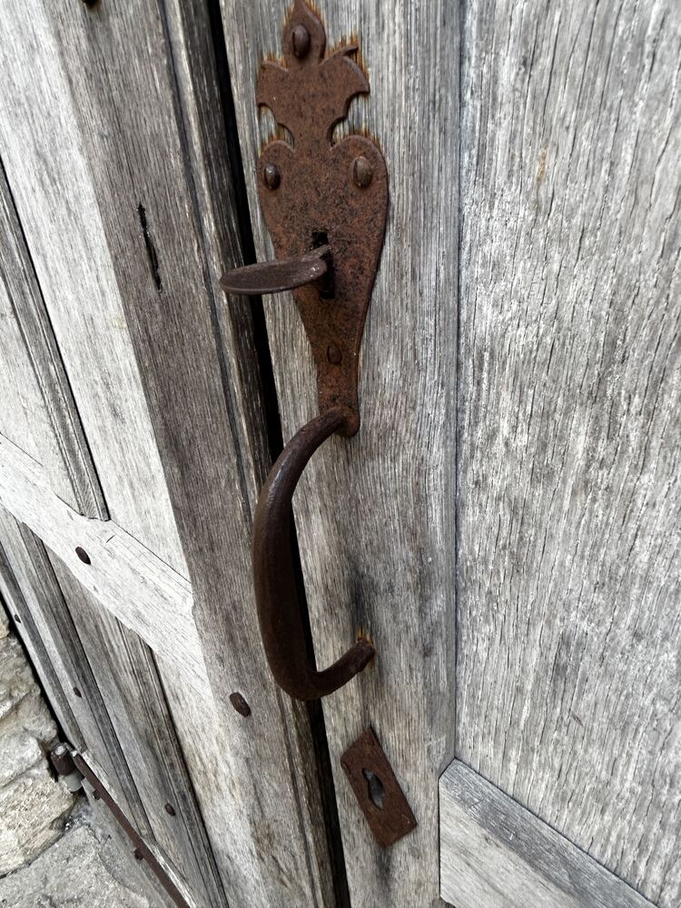 Ancienne poignée et loquet en fer forgé sur une porte en bois.