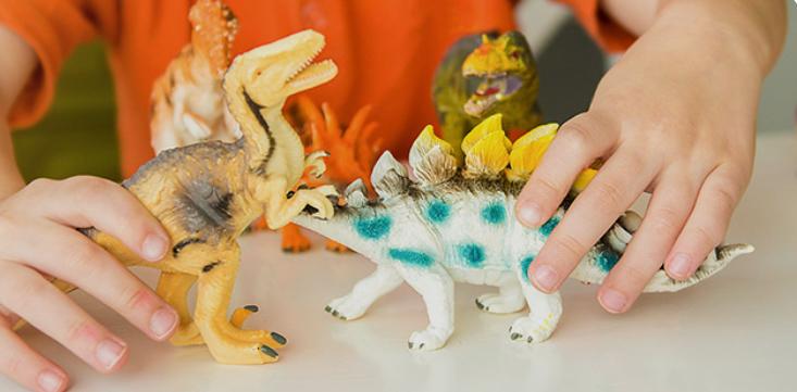 Enfant jouant avec des figurines de dinosaures.