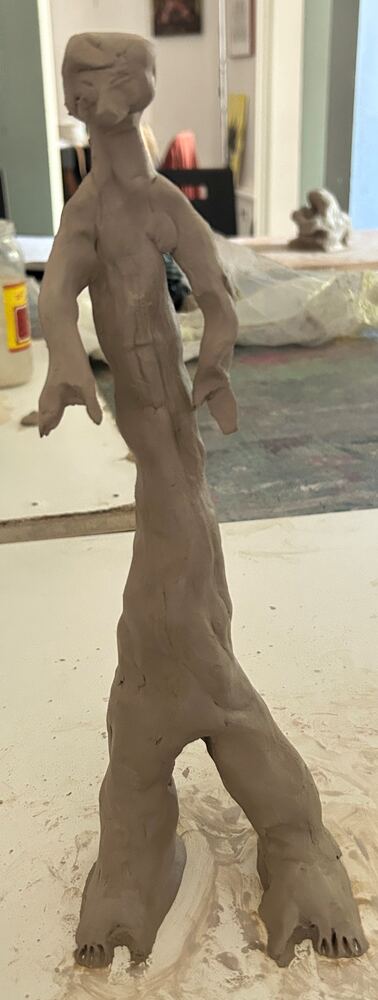 Silhouette humaine modelée en argile crue, réalisée en atelier.